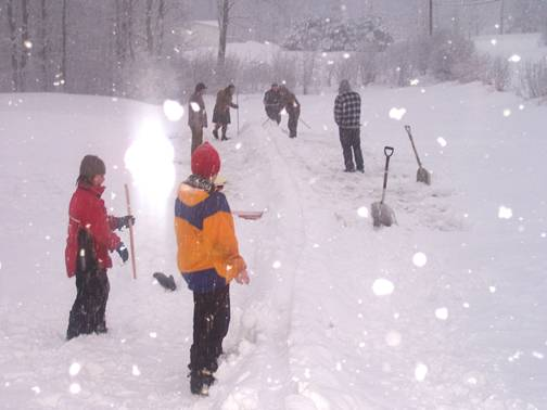 People standing next to a snow snakes track